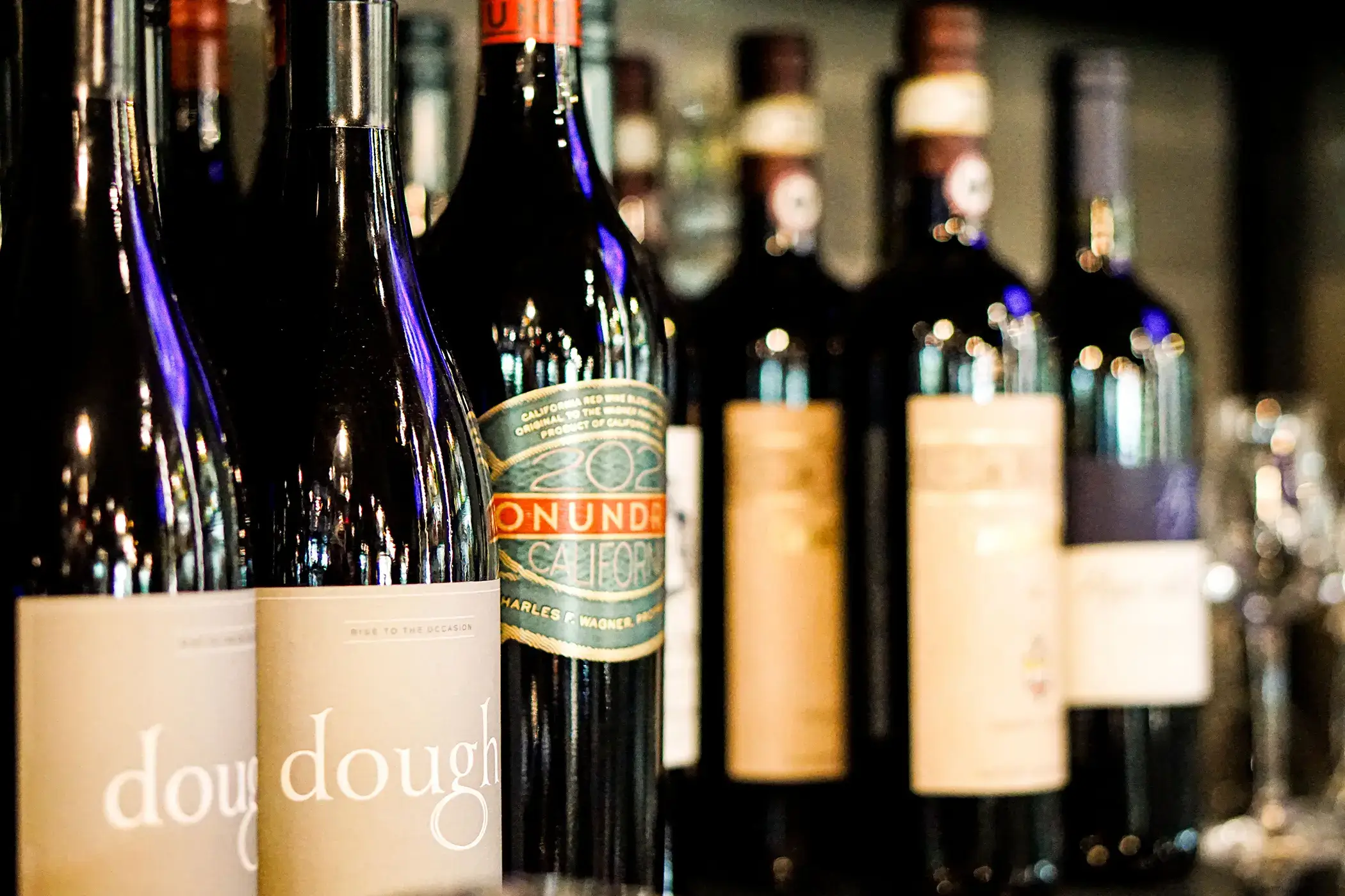 rule prime pasta closeup wine bottles on bar surface with detailed labels soft warm lighting hickory nc